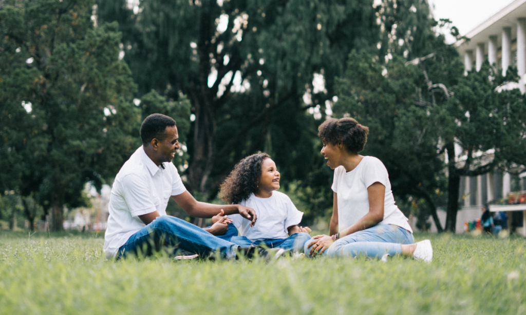 Family of three sitting on grass an encouragement to tell your story