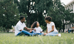 Family of three sitting on grass an encouragement to tell your story